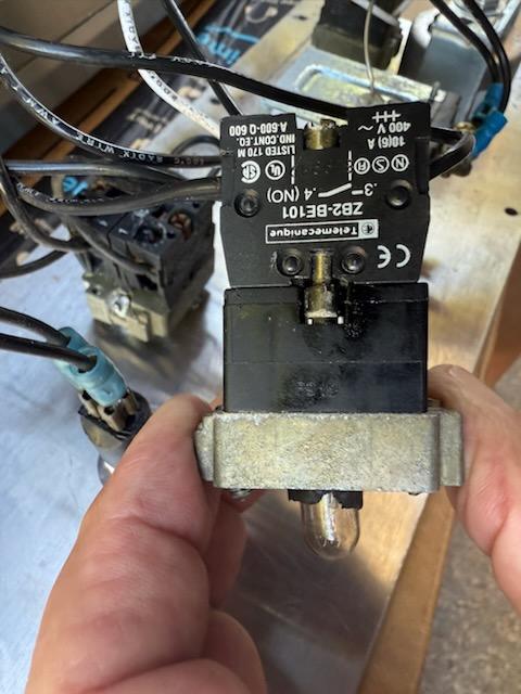 Back of a contact block switch assembly showing numbered wiring terminals and voltage rating label