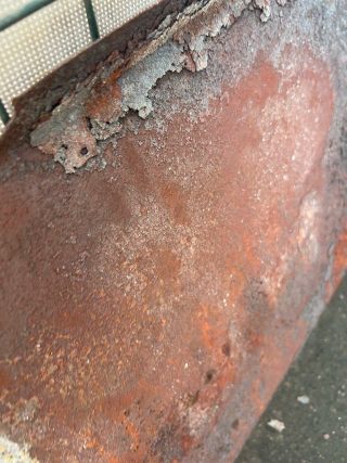 Close-up of corroded air deflector surface showing scaled and flaking rust